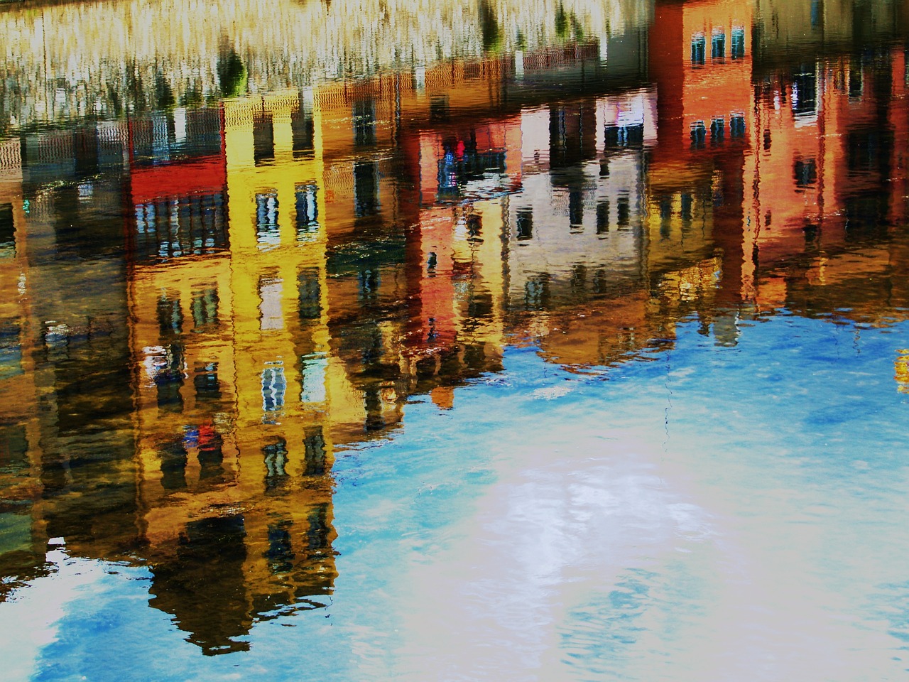 A painting of colorful buildings reflecting on the water.