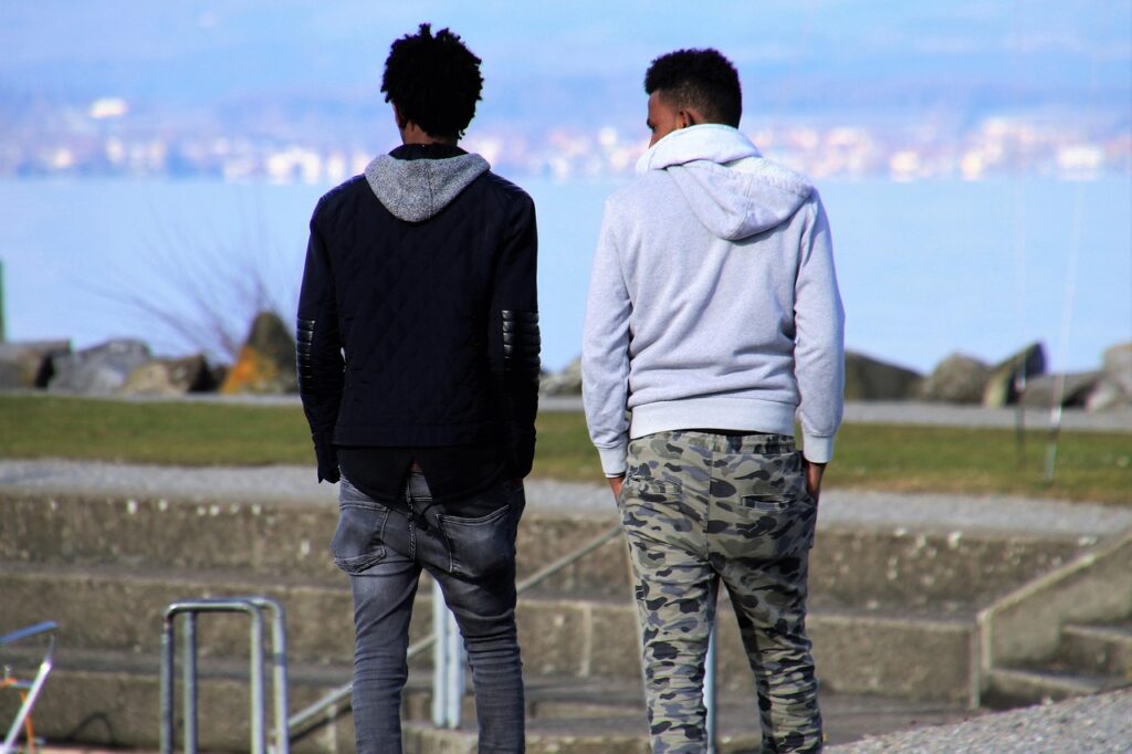 Two young men walking together with their hands in their pockets, and with their backs to the camera.