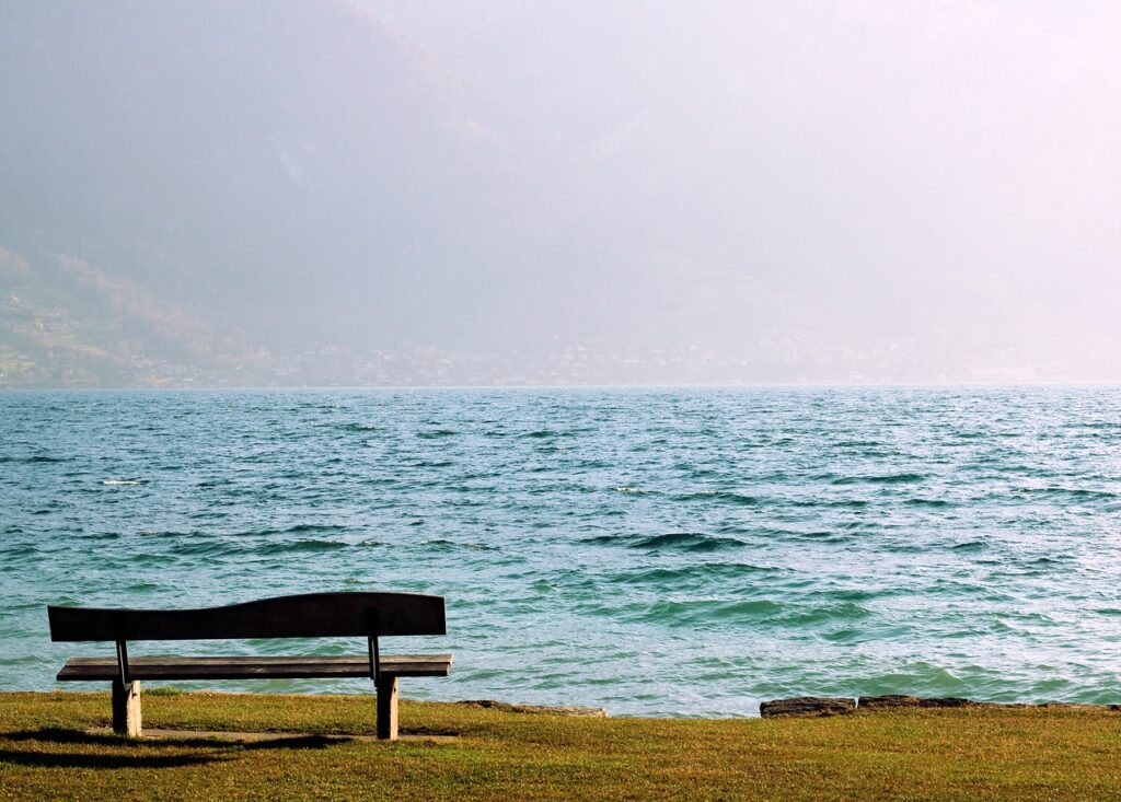 An empty bench in a park facing the blue ocean, finding a happy place.