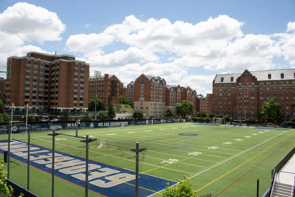 In daytime, part of a green football field from a college in D.C.